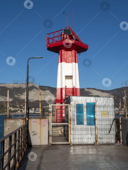 Скачать 22 августа 2025 года маяк у входа в порт Новороссийск, Россия, красный и белый на побережье Черного моря. Навигационное оборудование в порту фотосток Ozero