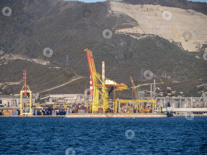 Скачать 22 августа 2025 года, вид порта Новороссийск, Россия, с грузовыми судами и кранами на побережье. Промышленный морской пейзаж на Черном море фотосток Ozero