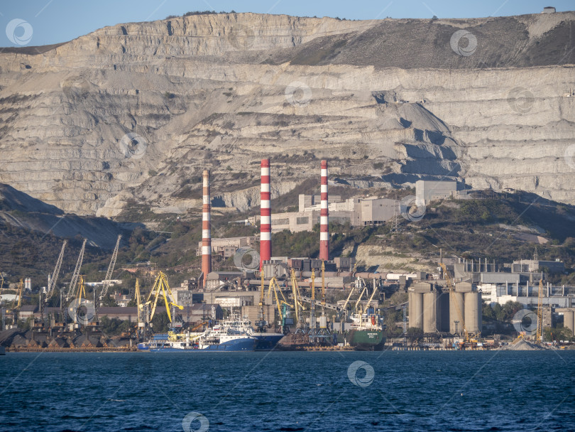 Скачать 22 августа 2025 года, вид порта Новороссийск, Россия, с грузовыми судами и кранами на побережье. Промышленный морской пейзаж на Черном море фотосток Ozero