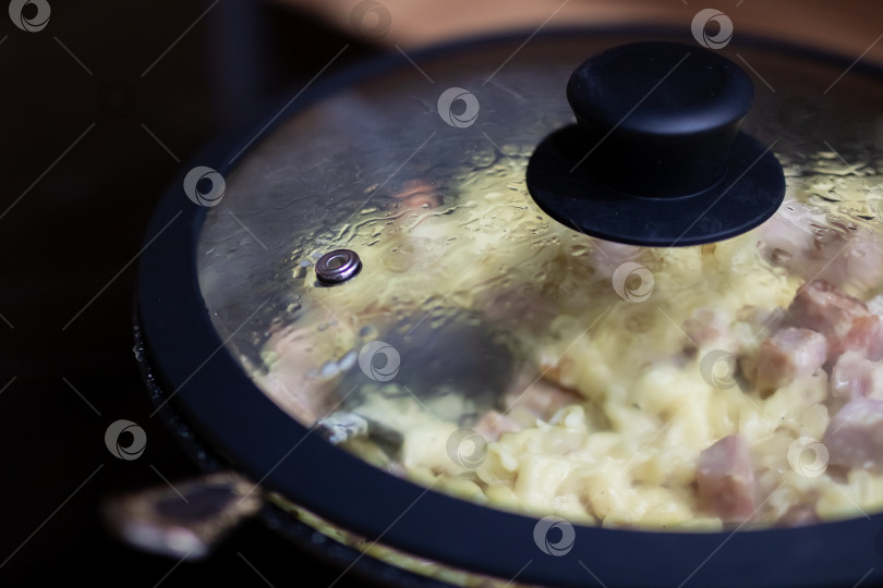 Скачать Воздух наполняется теплым кухонным ароматом. Аппетитный аромат поднимается от варящихся макарон и нарезанной ветчины фотосток Ozero