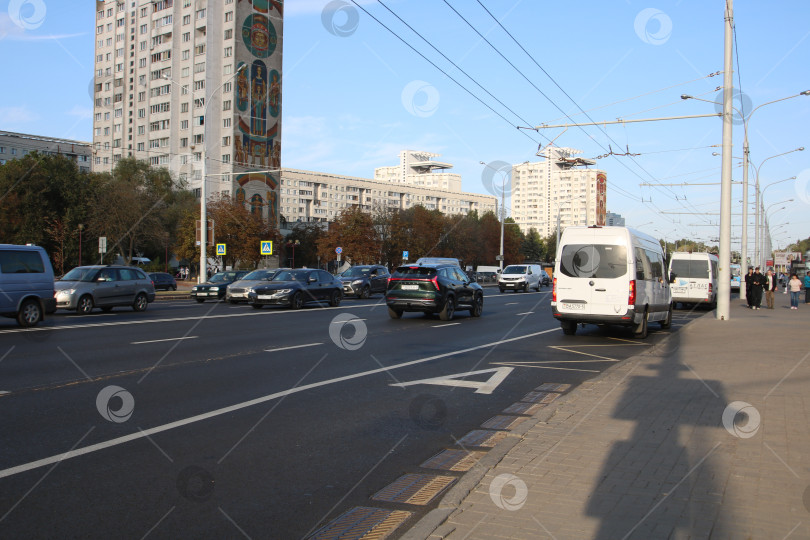 Скачать Беларусь, Минск - 22.09.2024: Оживленная улица с движением и тенями. Оживленный городской проспект, заполненный машинами и солнечным светом. фотосток Ozero