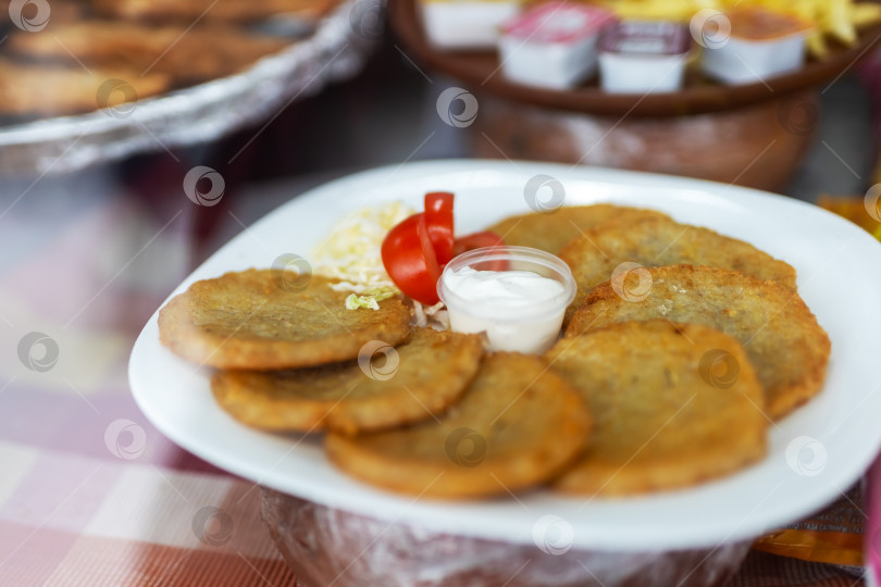 Скачать В уютном рыночном киоске подают хрустящие картофельные оладьи со сливками и ярким гарниром фотосток Ozero