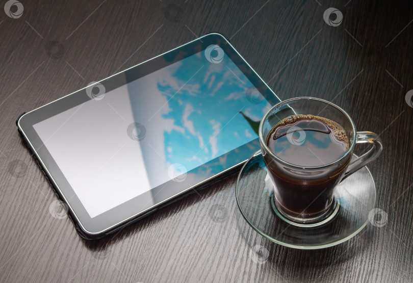 Скачать пейте черный кофе в кружке из прозрачного стекла на блюдце рядом с планшетом на деревянном столе фотосток Ozero