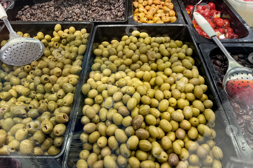 Скачать Маринованные оливки в лотке на прилавке продуктового магазина для пикантного готового салата ингредиенты фотосток Ozero