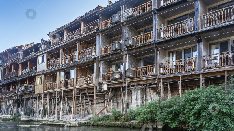 Скачать Старое деревянное здание на сваях на берегу реки. Балконы с перилами. фотосток Ozero