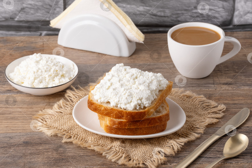 Скачать Сервировка завтрака с хлебом, творогом и кофе на деревянном столе в уютной кухонной обстановке фотосток Ozero