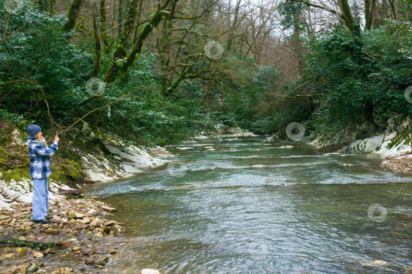 Скачать молодая женщина в синем плаще стоит на берегу горной реки. фотосток Ozero