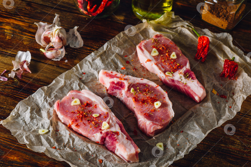 Скачать Три стейка из свиной корейки на пергаменте фотосток Ozero