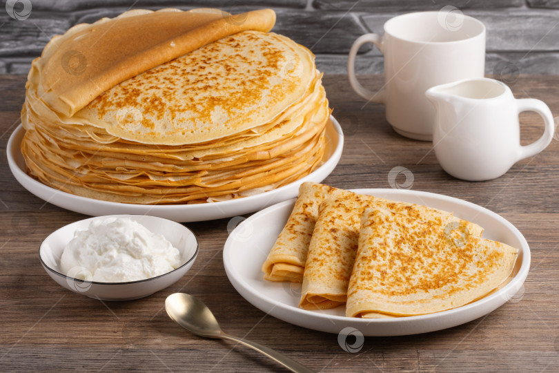 Скачать Традиционные русские блинчики со сметаной на деревянном столе. Домашние тонкие русские оладьи-блинчики. Русская кухня фотосток Ozero