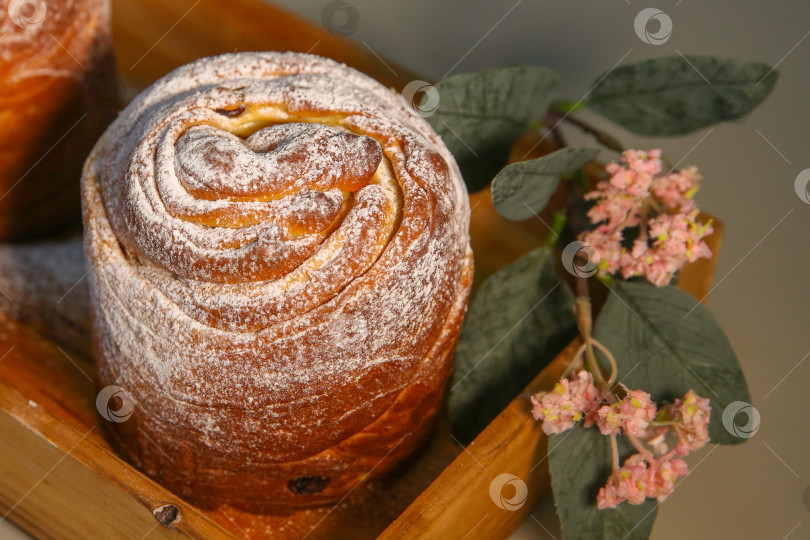 Скачать Пасхальный кекс краффин (craffin) с сахарной пудрой и декоративным цветком на столе фотосток Ozero