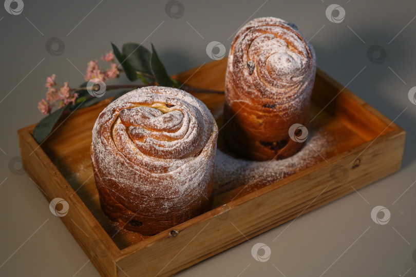 Скачать Пасхальный кекс краффин (craffin) с сахарной пудрой и декоративным цветком на столе фотосток Ozero