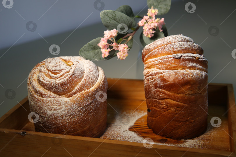 Скачать Пасхальный кекс краффин (craffin) с сахарной пудрой и декоративным цветком на столе фотосток Ozero