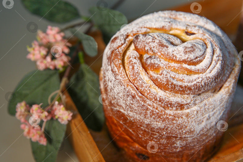 Скачать Пасхальный кекс краффин (craffin) с сахарной пудрой и декоративным цветком на столе фотосток Ozero