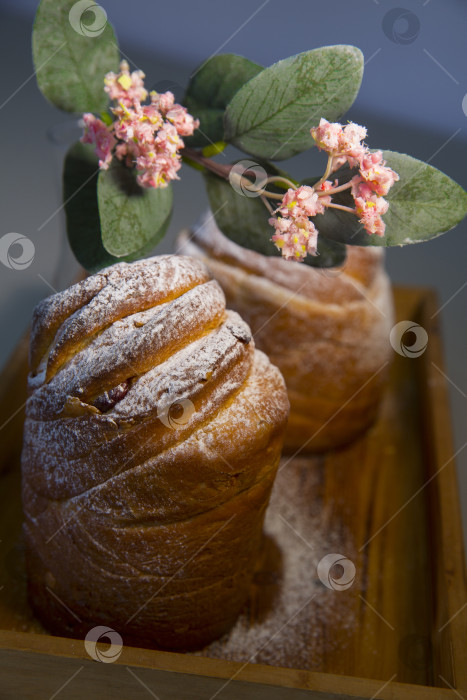Скачать Пасхальный кекс краффин (craffin) с сахарной пудрой и декоративным цветком на столе фотосток Ozero