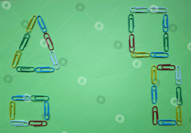 Скачать Треугольник, квадрат, прямоугольники из ярких разноцветных скрепок на зеленом фоне фотосток Ozero