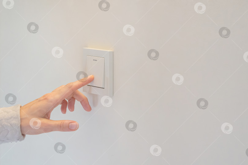 Скачать Женщина и нажимает на выключатель белого света на простой стене, копируя пространство фотосток Ozero