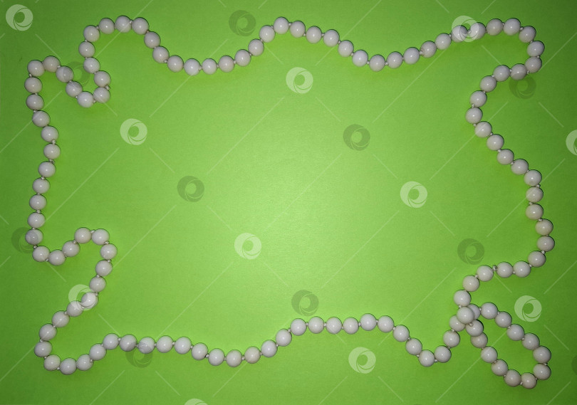 Скачать Нить с круглыми бусинами белого агата на зеленом фоне фотосток Ozero