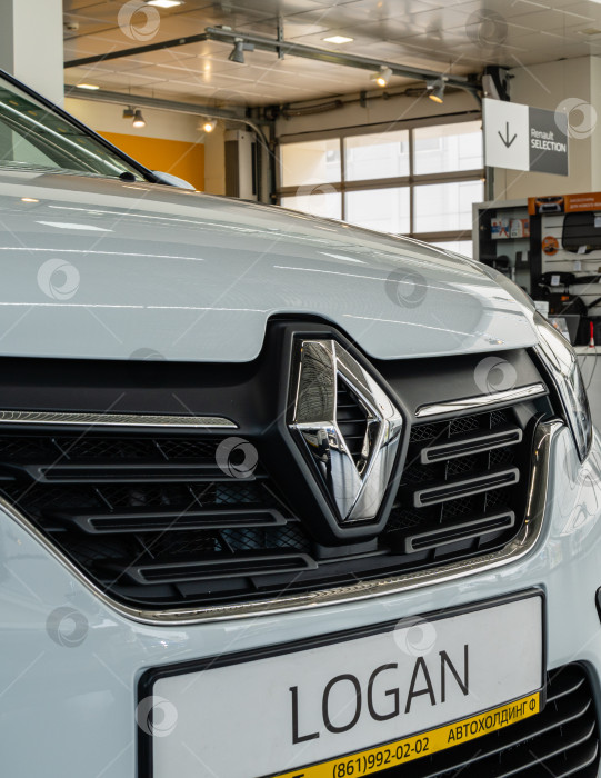 Скачать Белый Renault Logan в автосалоне Renault. Крупный план решетки радиатора автомобиля. Логотип Renault в центре решетки радиатора. Автосалон Renault в Мега Адыгея. Краснодар, Россия - 17 августа 2021 г. фотосток Ozero