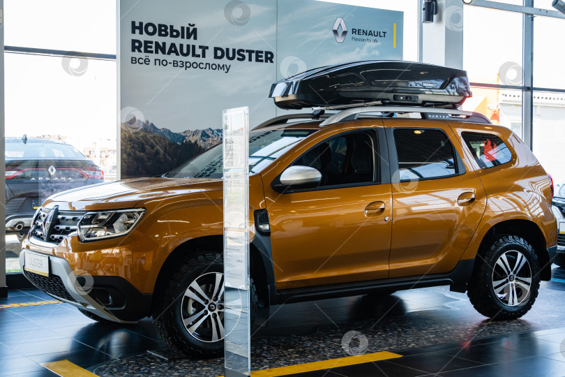 Скачать Внедорожник Renault Duster золотистого цвета с багажником на крыше в автосалоне Renault. Автомобиль крупным планом. Автосалон Renault в Мега Адыгея фотосток Ozero