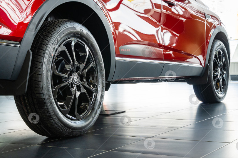 Скачать Красный внедорожник Renault Arkana в автосалоне. Шина Bridgestone установлена на литой алюминиевый обод. Крупный план заднего правого колеса. Автосалон Renault в Мега Адыгея. фотосток Ozero