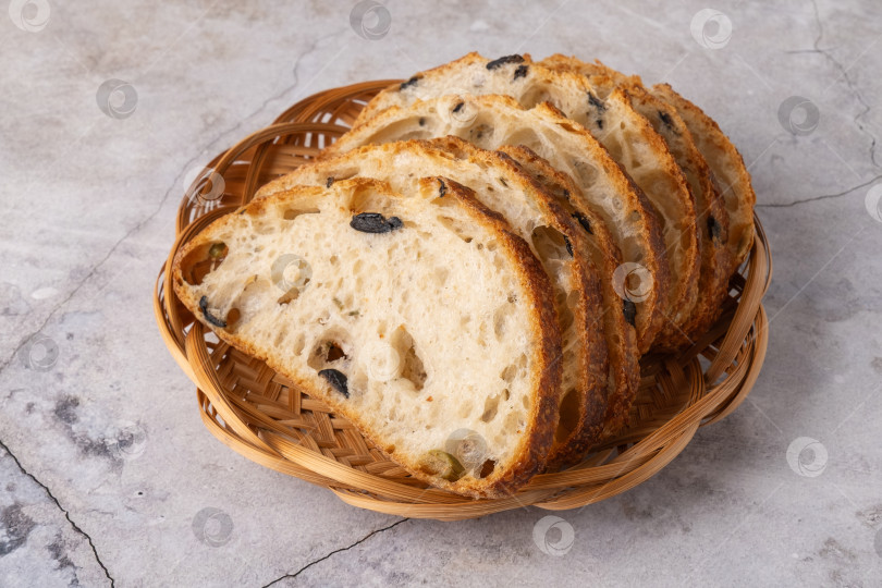 Скачать Домашний хлеб с оливками Каламата в плетеной корзинке, вид сбоку фотосток Ozero