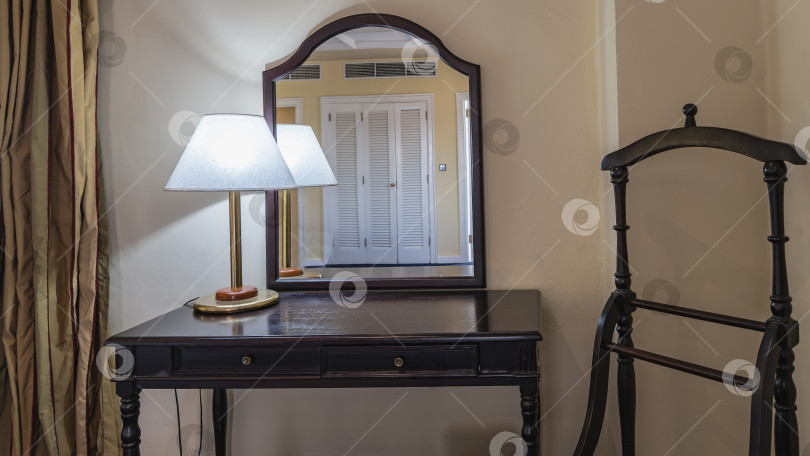Скачать Интерьер комнаты выполнен в стиле ретро. На туалетном столике из темного дерева горит лампа. фотосток Ozero