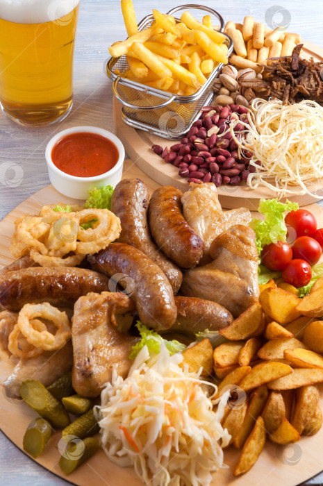 Скачать ассорти закусок к пиву: куриные крылышки, сосиски-гриль, картофель, орехи, сыр, гренки фотосток Ozero