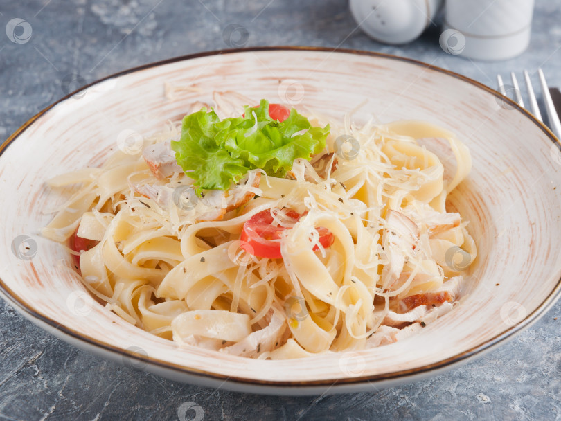 Скачать паста с курицей и помидорами, украшенная листьями салата фотосток Ozero