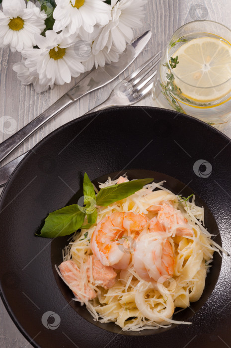 Скачать паста с морепродуктами: лососем, кальмарами, королевскими креветками на черной тарелке. Вид сверху фотосток Ozero