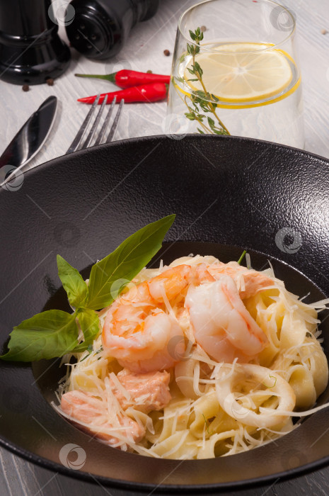 Скачать паста с морепродуктами: лососем, кальмарами, королевскими креветками на черной тарелке. фотосток Ozero