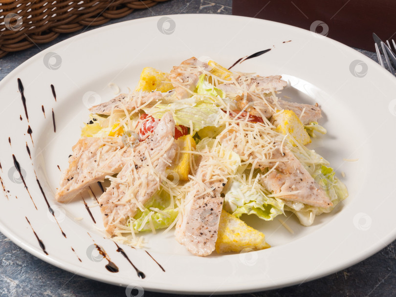 Скачать вкусный салат "Цезарь" с курицей на белой тарелке фотосток Ozero