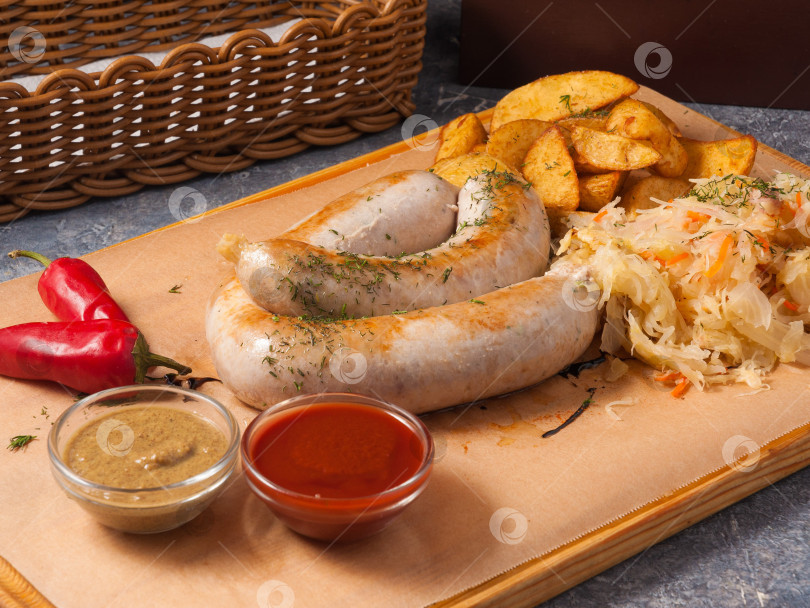 Скачать свиные сосиски с сыром и прованскими травами с ломтиками картофеля, капустой и соусами фотосток Ozero