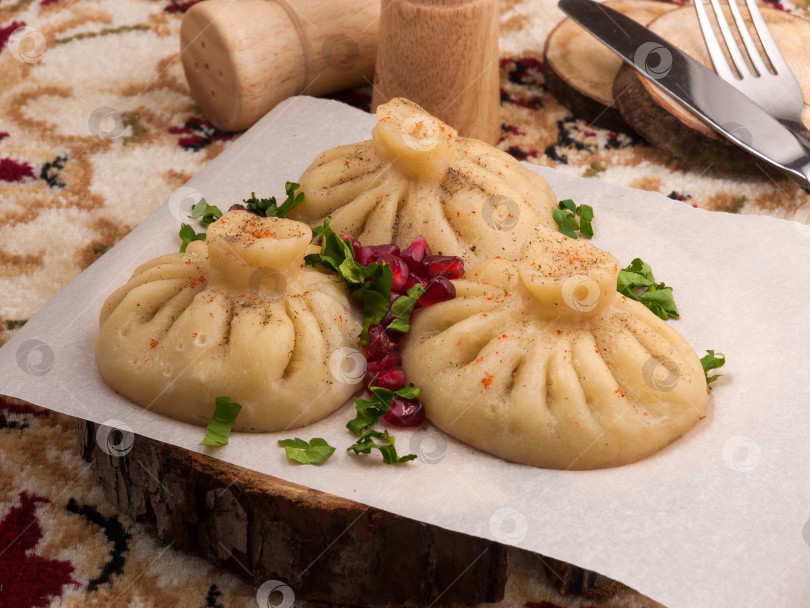 Скачать хинкали с говядиной, украшенные зернами граната и зеленью. закрыть фотосток Ozero
