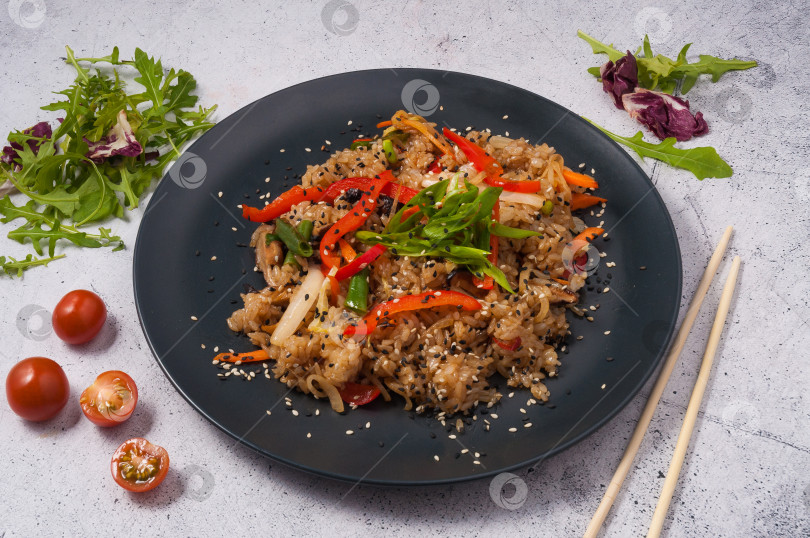 Скачать жареный рис с овощами на черной тарелке. Азиатская кухня фотосток Ozero