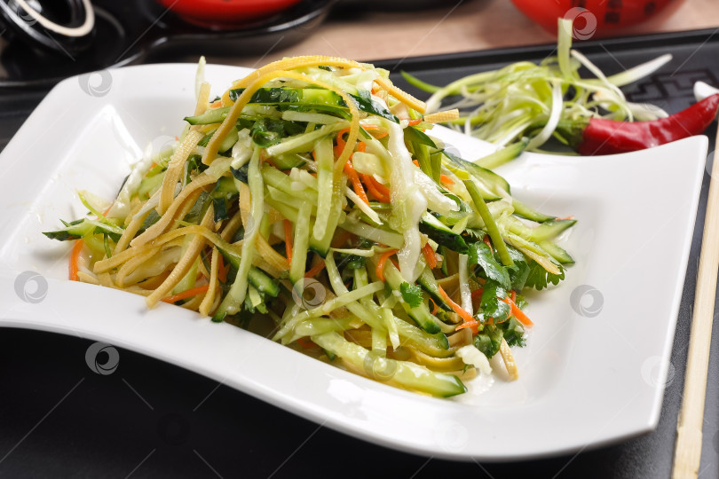 Скачать Китайская кухня: салат из огурцов с кукурузой на белой тарелке фотосток Ozero