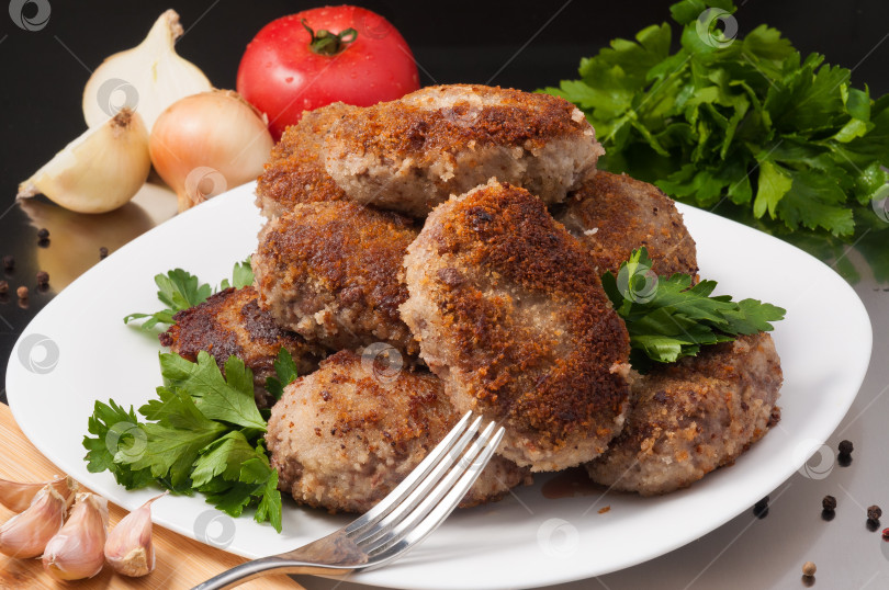 Скачать обжаренные мясные котлеты, украшенные овощами и зеленью фотосток Ozero