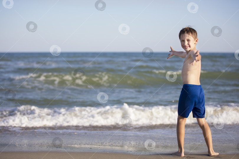 Скачать Радостный мальчик у моря раскрыл свои объятия. Ребенок отдыхает на пляже фотосток Ozero