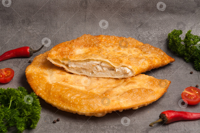 Скачать чебурек с курицей на сером фоне, украшенный зеленью и овощами фотосток Ozero