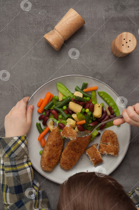 Скачать ребенок ест котлеты с овощами. вид сверху фотосток Ozero