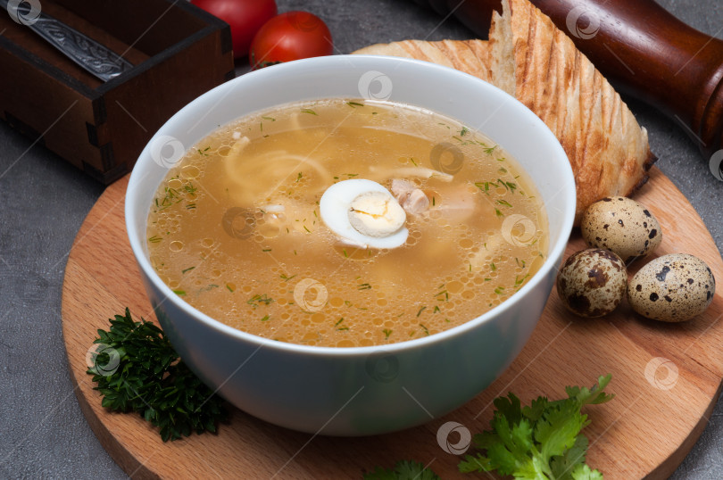 Скачать куриный суп с лапшой и перепелиным яйцом на деревянной доске фотосток Ozero