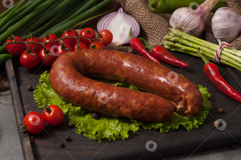 Скачать краковская колбаса на деревянной доске, украшенная свежими овощами фотосток Ozero