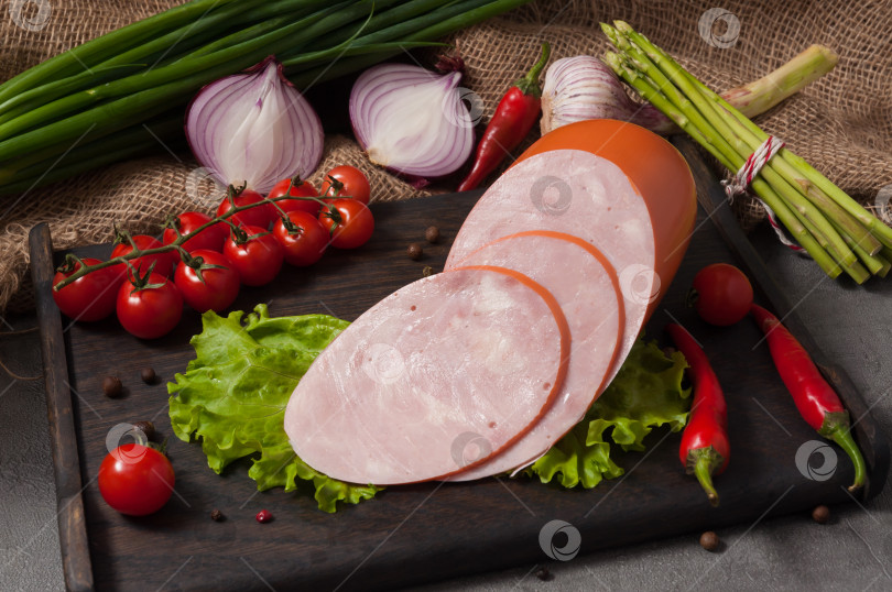 Скачать куриный окорок на деревянной доске, украшенный свежими овощами фотосток Ozero