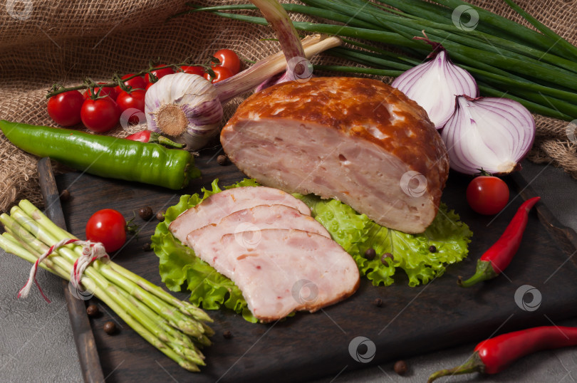 Скачать рулет из варено-копченой курицы на деревянной доске, украшенный свежими овощами фотосток Ozero