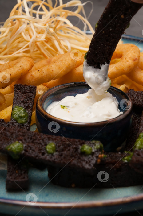 Скачать закуски к пиву: луковые кольца, чесночные гренки, сыр со сметанным соусом. Крупный план фотосток Ozero