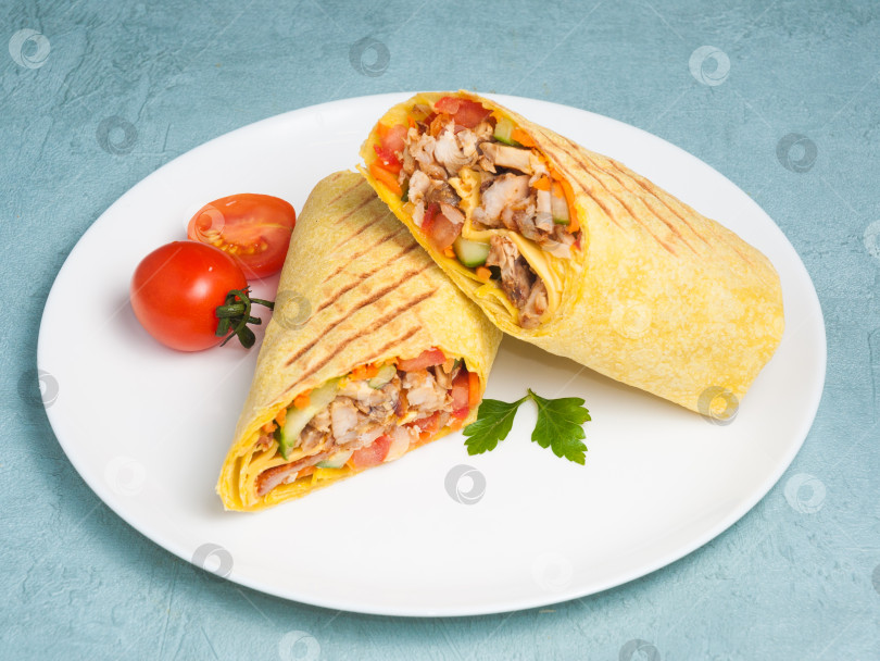 Скачать шаурма с курицей и овощами в сырном лаваше на синем фоне. фотосток Ozero