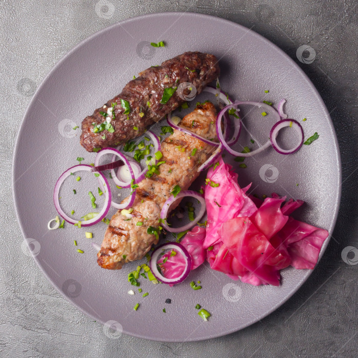 Скачать люля-кебаб из свинины и говядины с маринованной капустой и красным луком. вид сверху фотосток Ozero