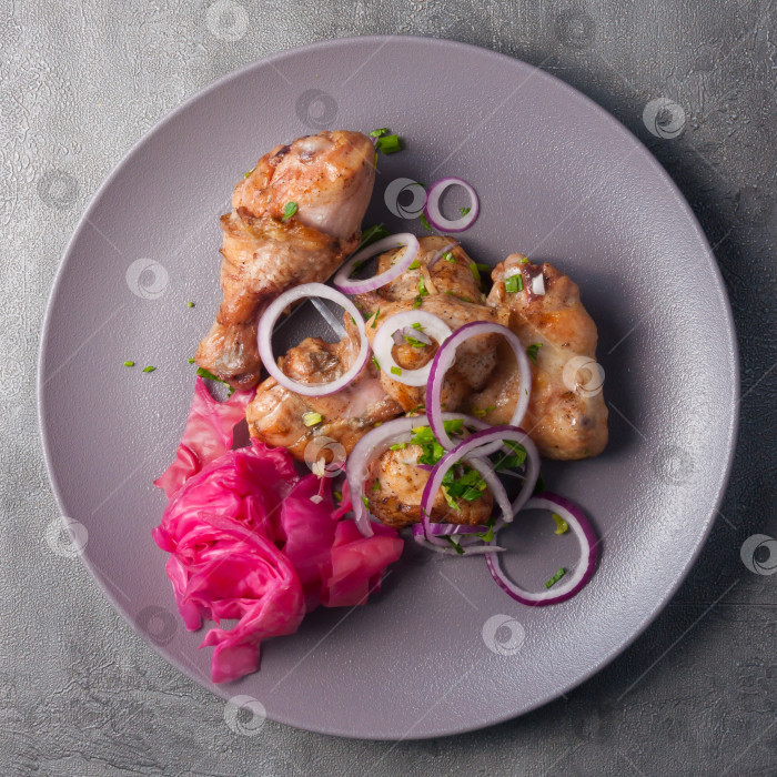 Скачать жареный цыпленок с маринованной капустой, украшенный красным луком. вид сверху фотосток Ozero