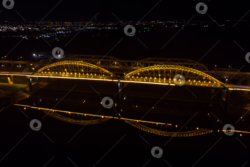 Скачать Яркие огни, мосты с арками, ночной город. Автомобильный мост через реку, снятый с беспилотника. фотосток Ozero