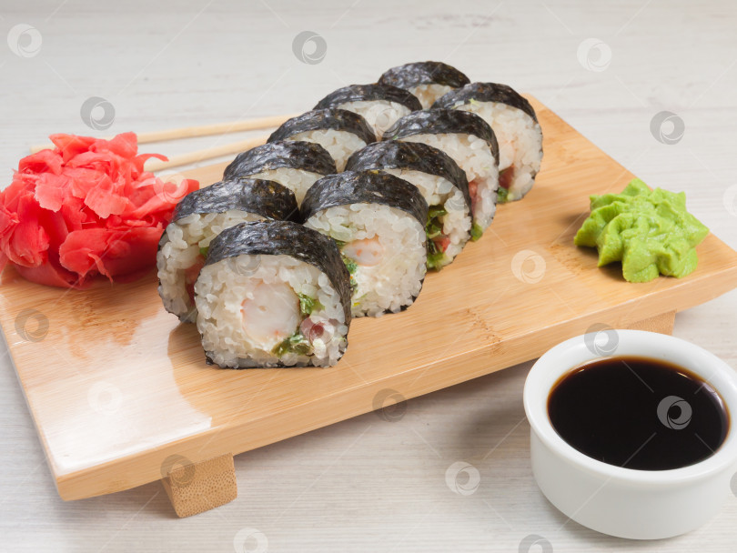 Скачать суши-роллы с креветками, чукой, помидорами и сливочным сыром на деревянной доске фотосток Ozero