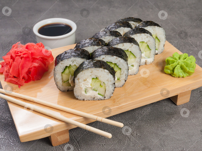 Скачать суши-роллы с огурцом и сливочным сыром на деревянной доске фотосток Ozero